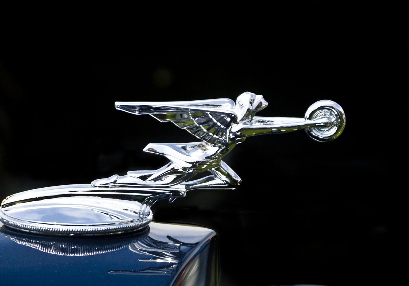 A close up of the hood ornament on an antique car.